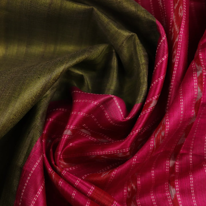 Close-up view of the luxurious texture of a plain green Tussar silk saree with a magenta border