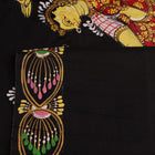 Close-up of black silk Patachitra saree fabric texture showing hand-painted details.