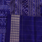Close-up of red Sambalpuri silk saree fabric showing intricate woven motif texture and subtle blue threads.
