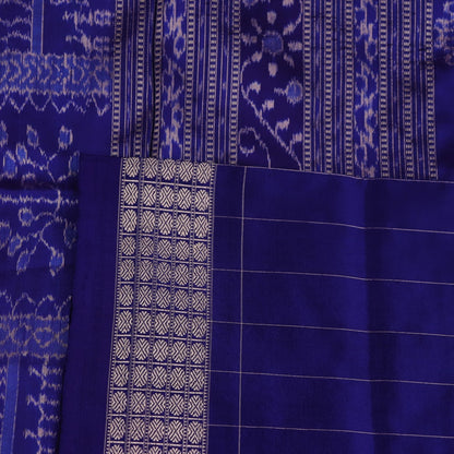 Close-up of red Sambalpuri silk saree fabric showing intricate woven motif texture and subtle blue threads.