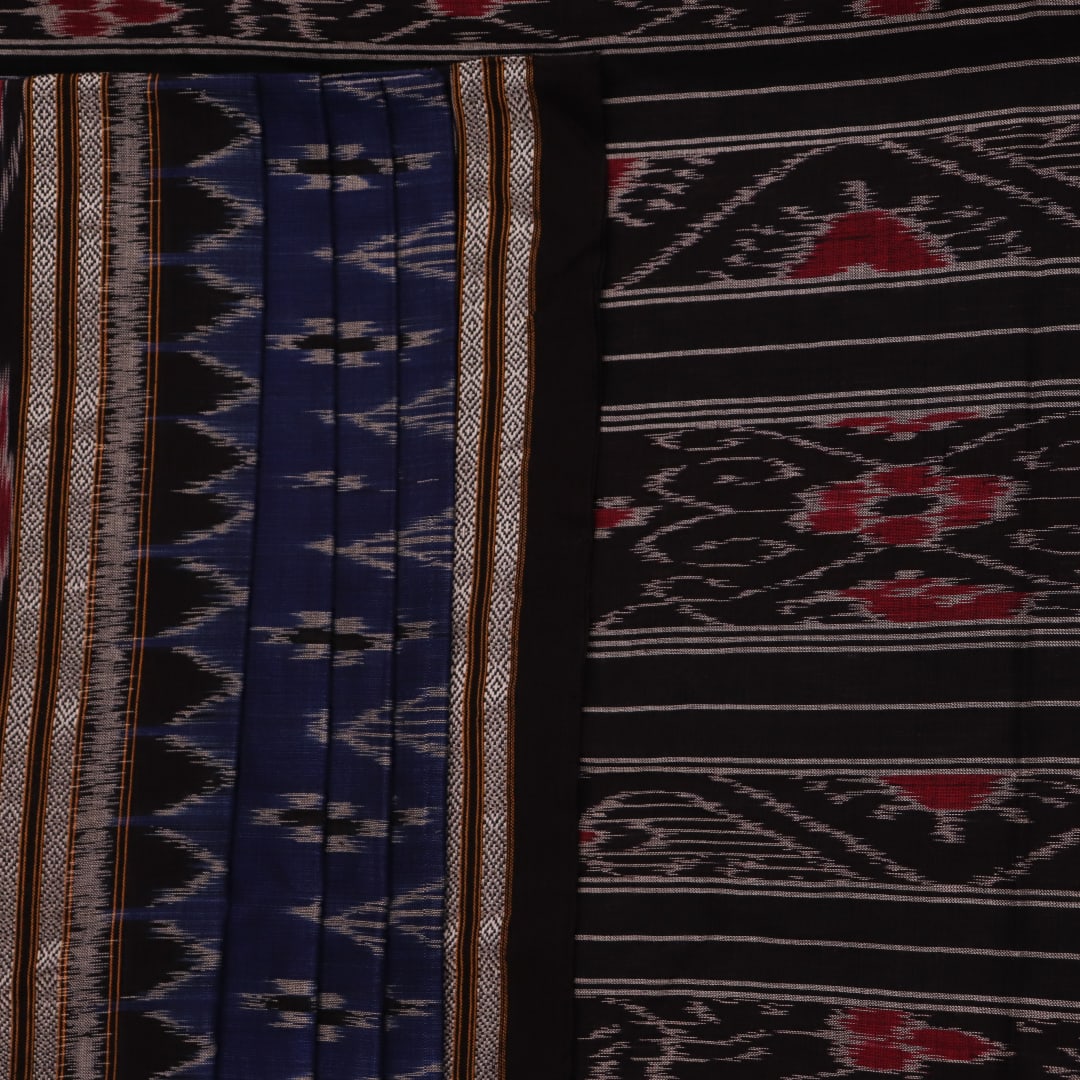 A person wearing a vibrant blue cotton Sambalpuri saree with black motifs, styled in a traditional drape.