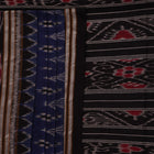 A person wearing a vibrant blue cotton Sambalpuri saree with black motifs, styled in a traditional drape.