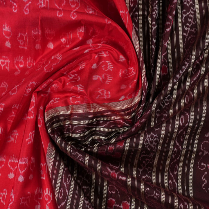Ultra close-up of the red Sambalpuri silk saree fabric, revealing its luxurious texture and handloom weave.