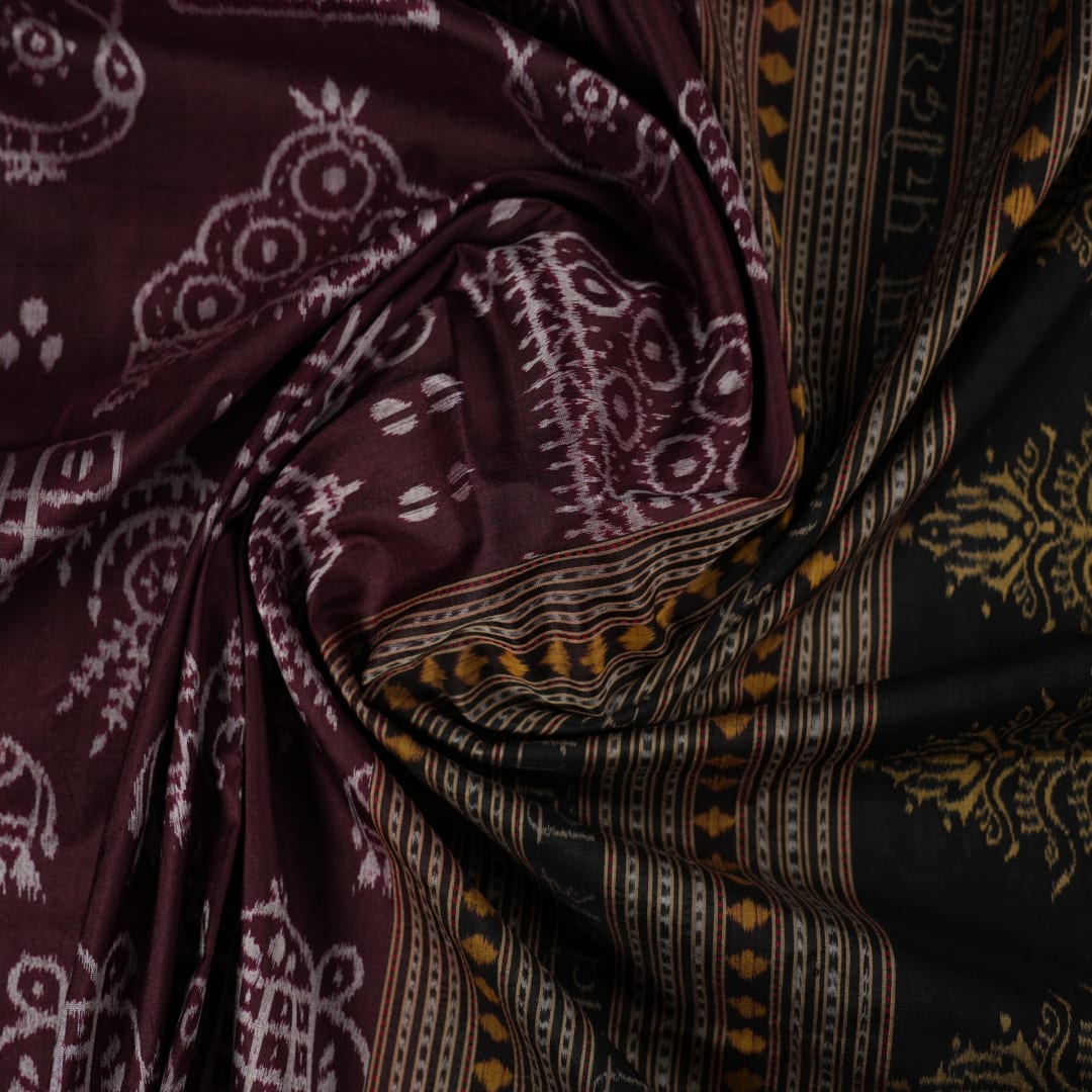 Micro close-up of the maroon Sambalpuri silk fabric, revealing its luxurious texture and handloom weave.