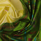Close-up of cream and green Bomkai Silk Saree fabric texture with butta pattern.