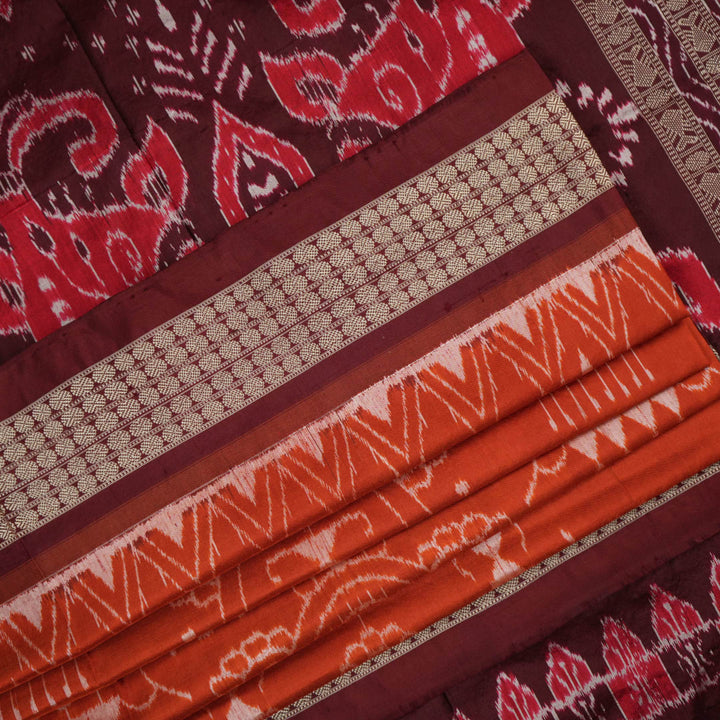 Extreme close-up of the lustrous rust Sambalpuri silk fabric, showing its fine weave and subtle motif texture.