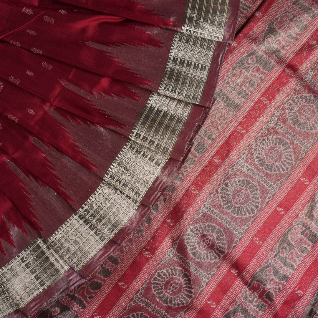Extreme close-up revealing the rich texture and intricate handloom weave of the maroon and grey Sambalpuri silk fabric.