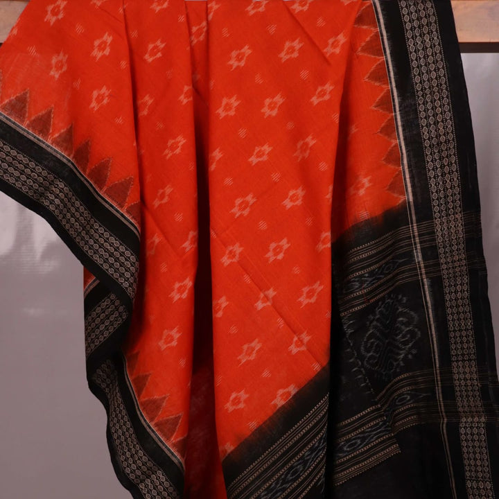 Full body view of a folded Sambalpuri cotton dupatta in orange with bold black motifs.