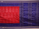Close-up of red Sambalpuri silk saree fabric showing intricate woven motif texture and subtle blue threads.