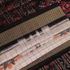 Close-up of handloom Sambalpuri silk saree fabric texture; white with subtle black motifs.