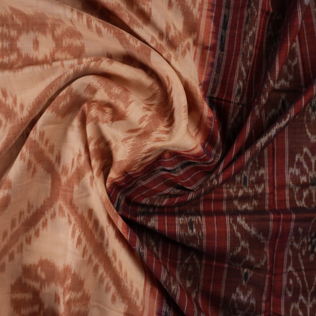 Traditional styling of a cream and rust Sambalpuri cotton saree draped on a model for a classic look.