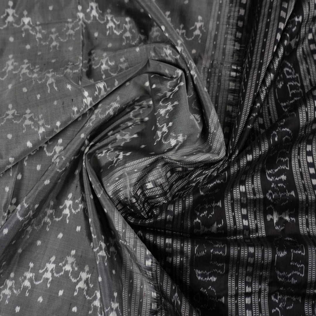 Close-up of grey & black Sambalpuri silk saree fabric, highlighting its rich texture and weave.