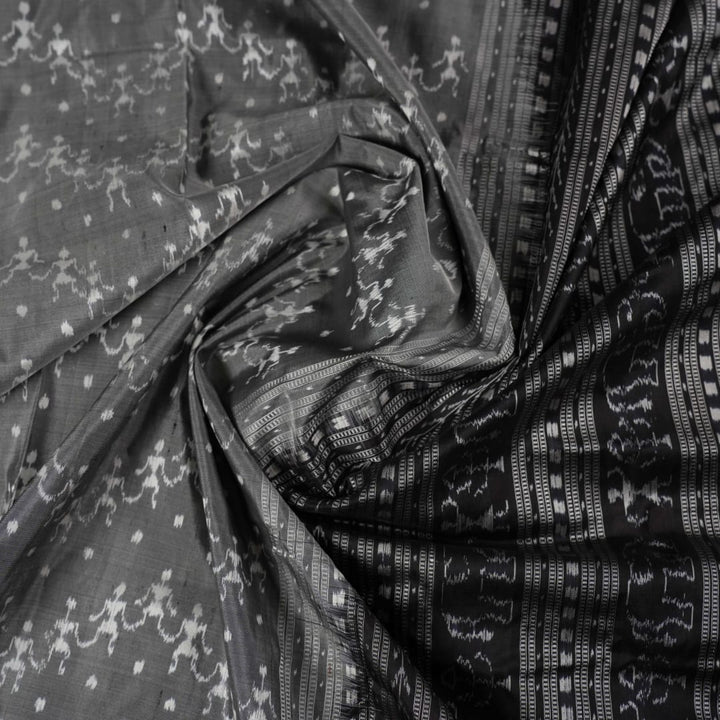 Close-up of grey & black Sambalpuri silk saree fabric, highlighting its rich texture and weave.