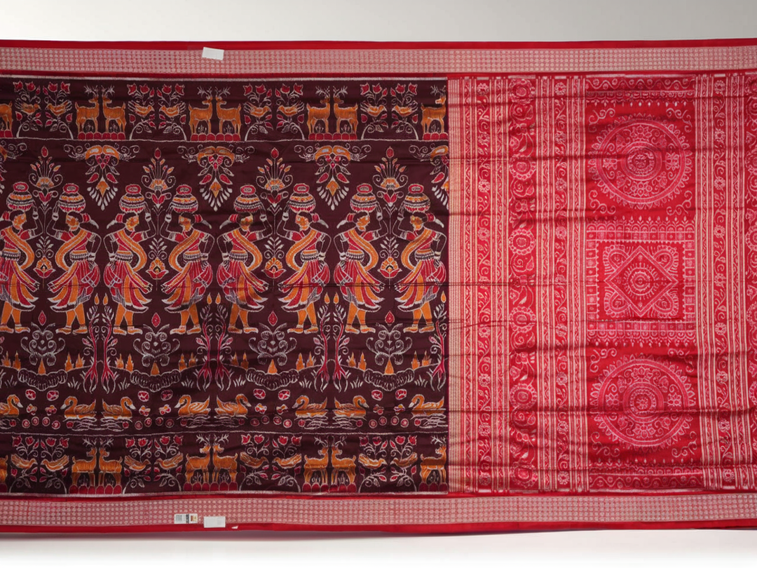 Close-up of the maroon Sambalpuri silk saree fabric, highlighting its luxurious texture and intricate weave.