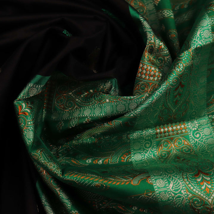 Close-up view of black silk Bomkai saree, showcasing intricate butta patterns and green accents