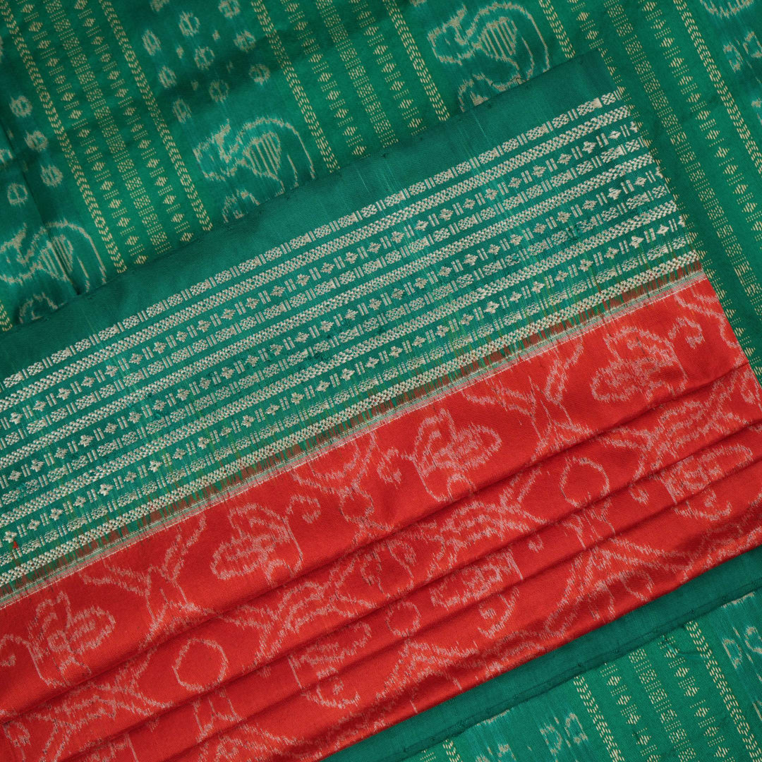Extreme close-up of the rich orange Sambalpuri silk fabric, highlighting its intricate handloom weave texture.