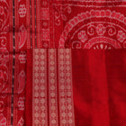 Close-up of grey Sambalpuri silk saree fabric showing intricate woven motifs and texture.