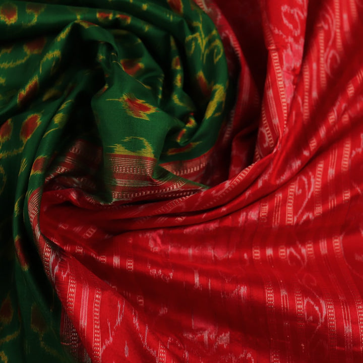 Close-up of green and orange silk Sambalpuri saree fabric with intricate motif patterns