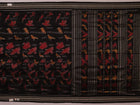 Close-up of the textured silk fabric of a black Sambalpuri saree showing intricate motifs.
