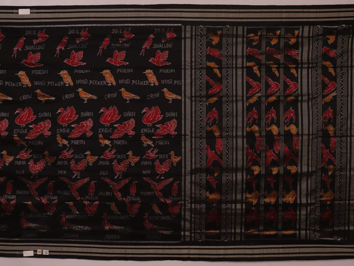 Close-up of the textured silk fabric of a black Sambalpuri saree showing intricate motifs.