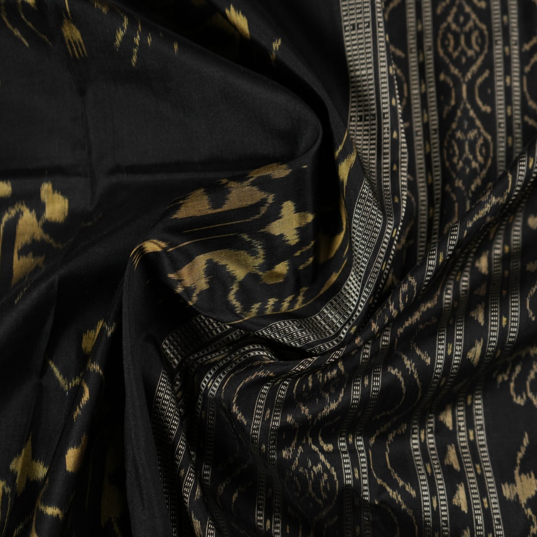 Close-up of the lustrous black Sambalpuri silk fabric, revealing its luxurious texture and fine weave.