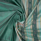 Extreme close-up of the green Sambalpuri silk fabric, revealing its luxurious texture and fine handloom weave.