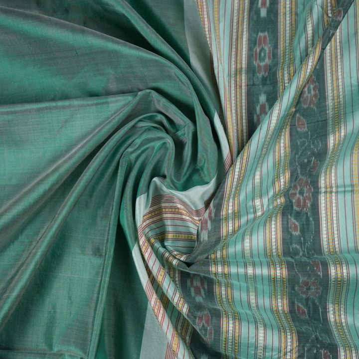 Extreme close-up of the green Sambalpuri silk fabric, revealing its luxurious texture and fine handloom weave.
