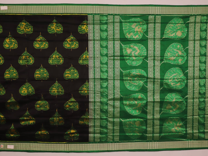 Close-up of the finely textured silk fabric in black, adorned with intricate Sambalpuri motifs in green