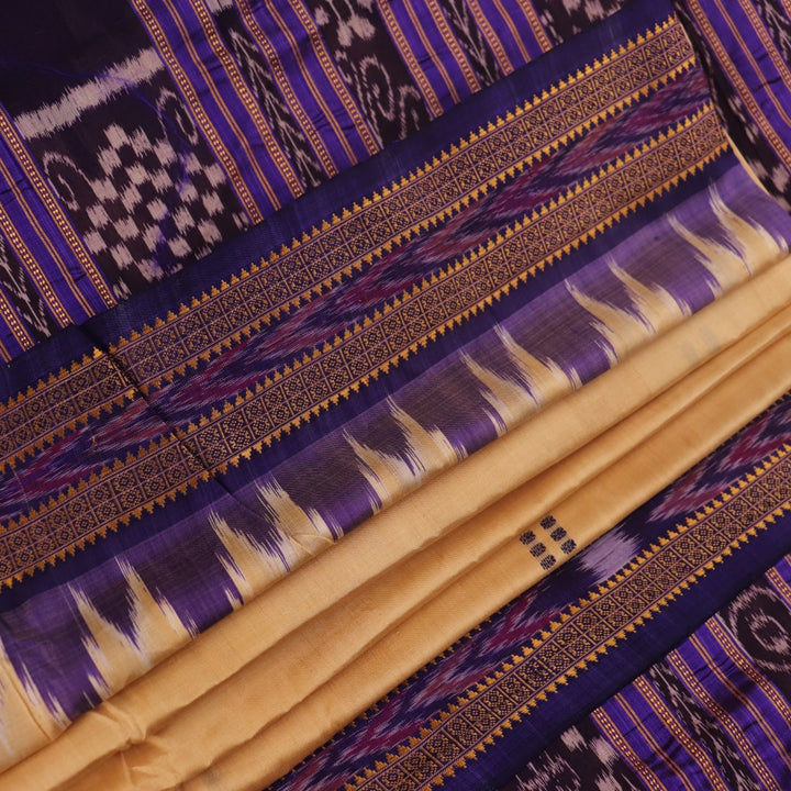 Woman draped in a cream and blue Khandua silk saree with butta pattern, showcasing the elegant drape and styling.