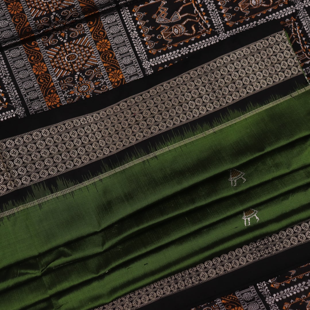 Close-up view of the silken texture of the Sambalpuri silk saree, showcasing green and black woven motifs.