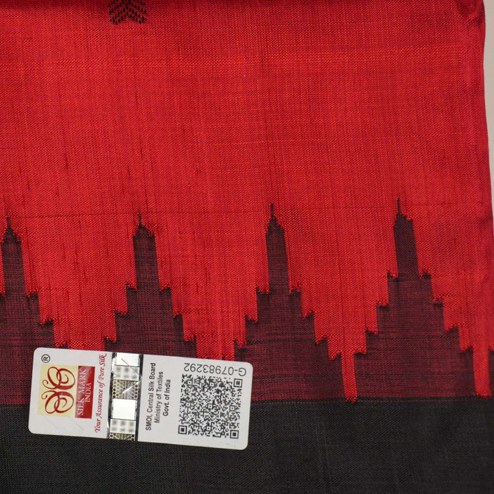 Detailed view of hand-woven silk fabric texture and butta patterns on a red Sambalpuri saree.