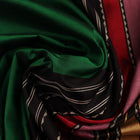 A close-up view of the lush, green silk fabric with a black butta pattern woven in.