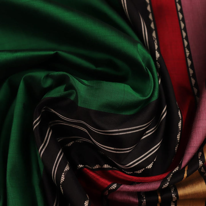 A close-up view of the lush, green silk fabric with a black butta pattern woven in.