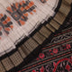 Close-up of handloom Sambalpuri silk saree fabric texture; white with subtle black motifs.