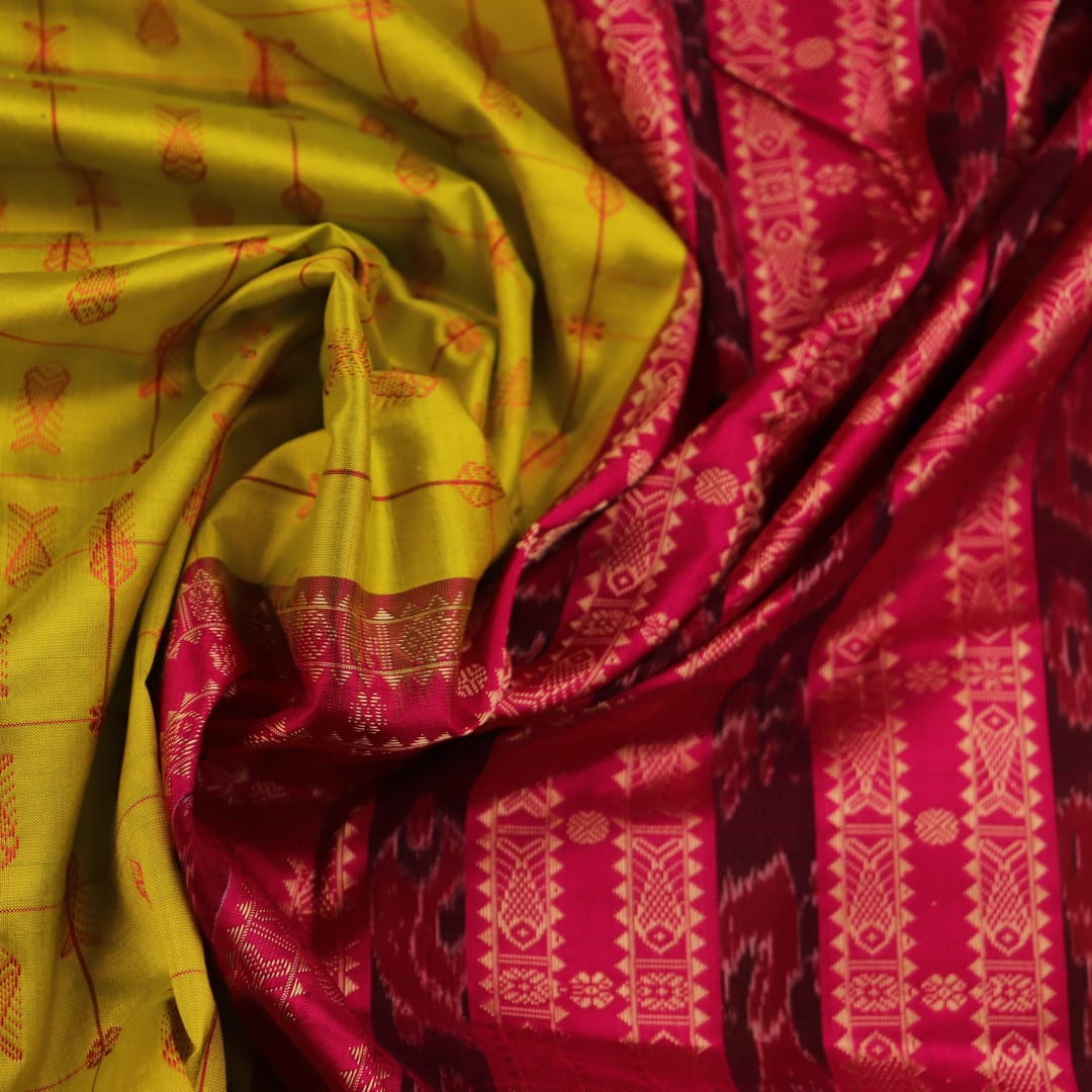 Close-up view of the soft silk fabric texture of a green and magenta Sambalpuri saree with intricate butta patterns