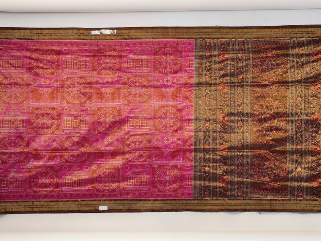 Close-up of Sambalpuri silk fabric texture, highlighting the fine weave in pink and maroon with delicate tissue motifs.
