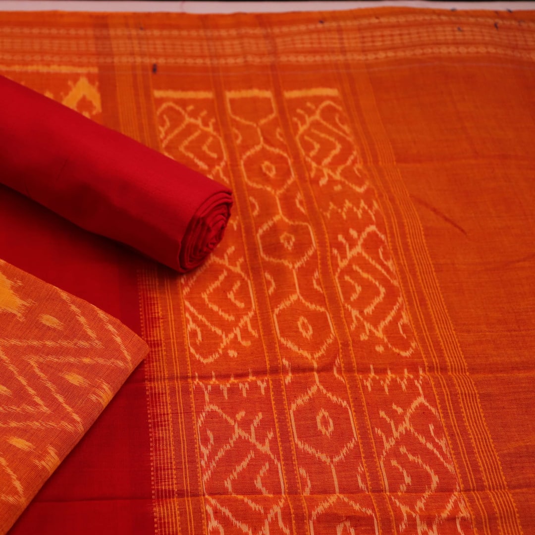 Close-up detail showcasing the traditional motifs in orange and red on cotton Sambalpuri dress material.