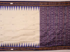 Woman elegantly draped in a white and blue Khandua silk saree with butta pattern.