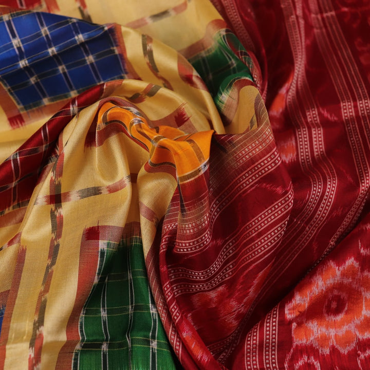 Close-up of multicolored Sambalpuri silk saree fabric texture showing intricate weave and maroon accents.