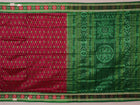 Close-up of magenta Sambalpuri silk saree fabric texture, showcasing intricate handloom weave and subtle motifs.