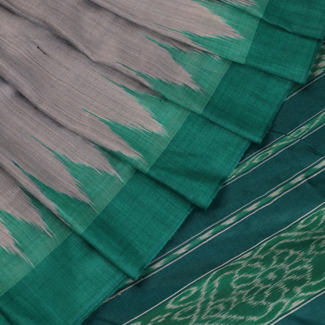 Close-up of textured grey and green Tussar silk fabric used in a plain pattern saree