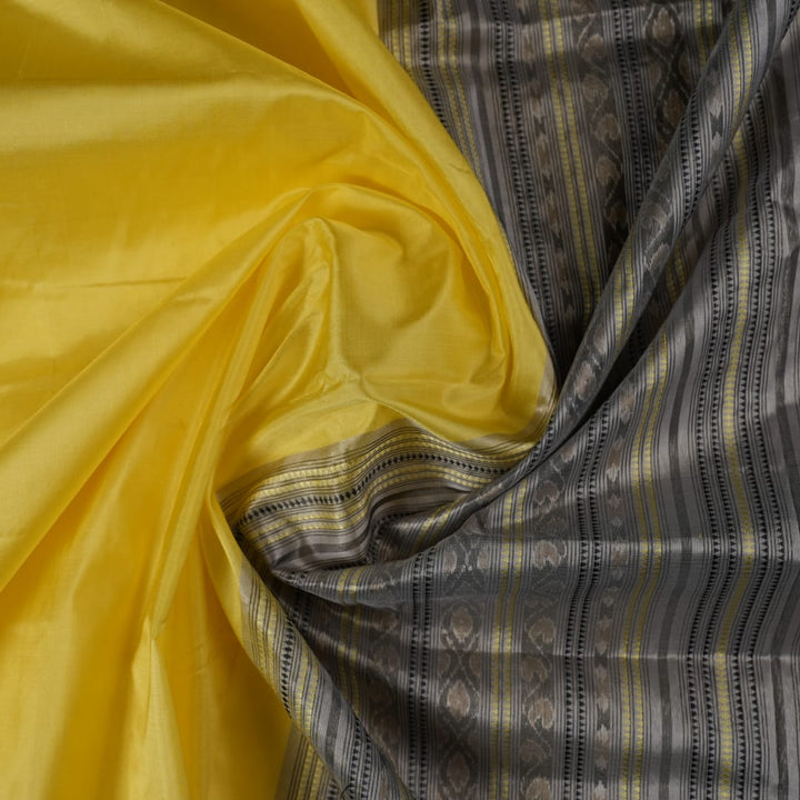 Close-up of the luxurious yellow Sambalpuri silk fabric, showing its fine weave and texture.