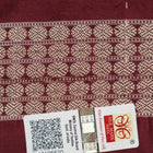 Extreme close-up of the lustrous rust Sambalpuri silk fabric, showing its fine weave and subtle motif texture.