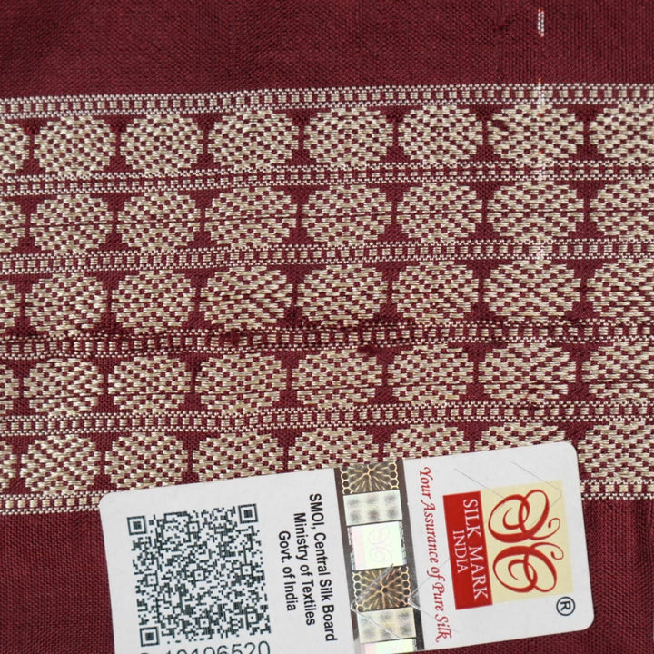 Extreme close-up of the lustrous rust Sambalpuri silk fabric, showing its fine weave and subtle motif texture.