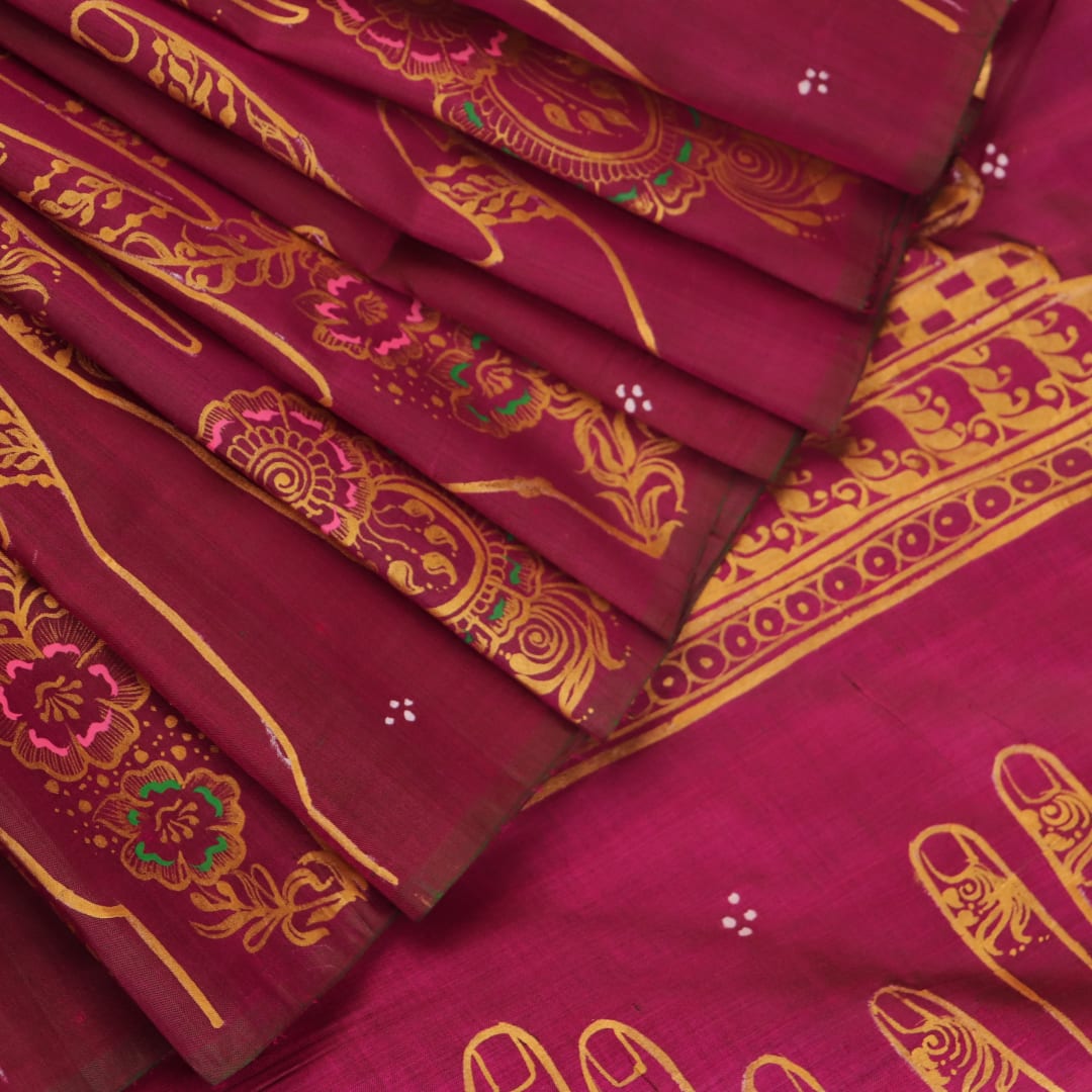 Close-up of magenta Patachitra silk saree fabric texture showing handloom weave and paint details.