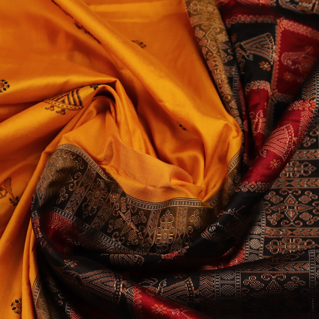 Close-up showcasing the smooth, golden-yellow silk texture of the Bomkai saree, adorned with intricate black butta patterns.