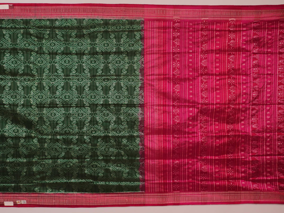 Close-up of textured green Sambalpuri silk saree fabric with magenta motifs.