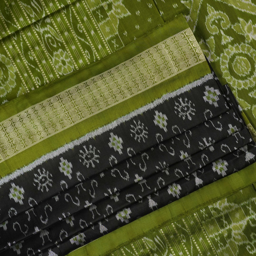Close-up of the luxurious black and green Sambalpuri silk fabric texture and weave.