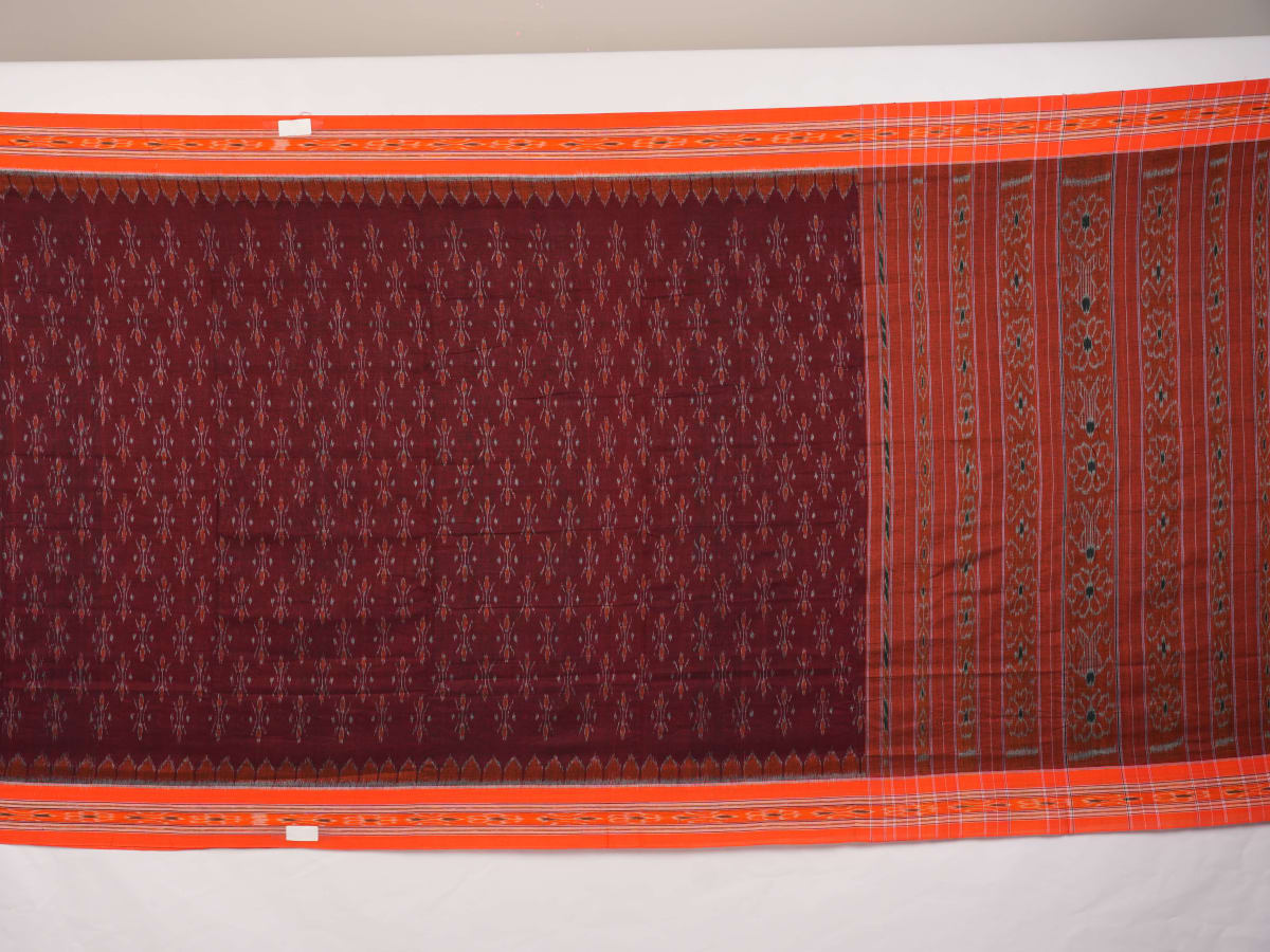 Model draped in a maroon and orange Sambalpuri cotton saree showcasing traditional handloom motifs.