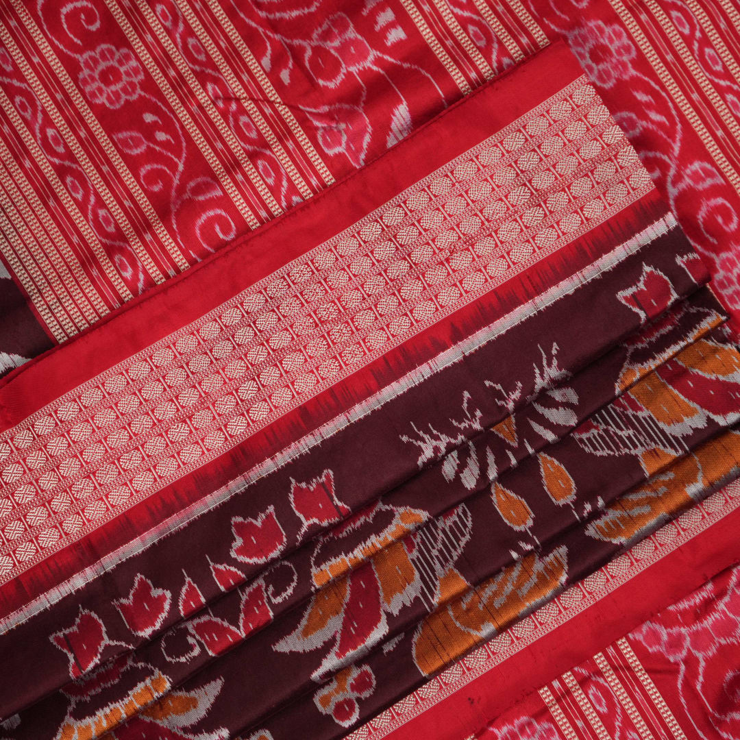 Close-up of the maroon Sambalpuri silk saree fabric, highlighting its luxurious texture and intricate weave.